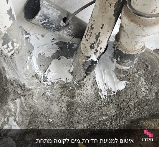 חומר איטום לבן סביב צינורות מתכת על קיר